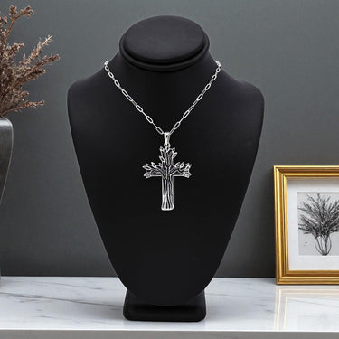 Silver necklace with a tree pendant on a black bust against a gray background